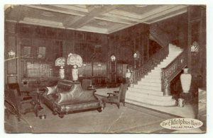 A black-and-white postcard depicting the lobby of the haunted Adolphus Hotel. The lobby is empty of the living, but the ghost of a jilted bride-to-be lurks just beyond the 19th floor. 